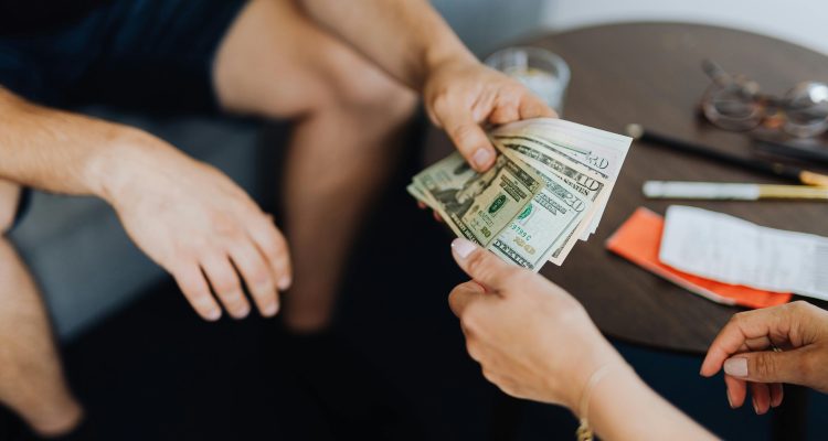 sugar-daddy-allowance-money-exchange › Sugarbook | No.1 Trusted Sugar Daddy & Real Sugar Baby Platform in the U.S. Hands exchanging US dollars as part of a Sugar Daddy allowance arrangement