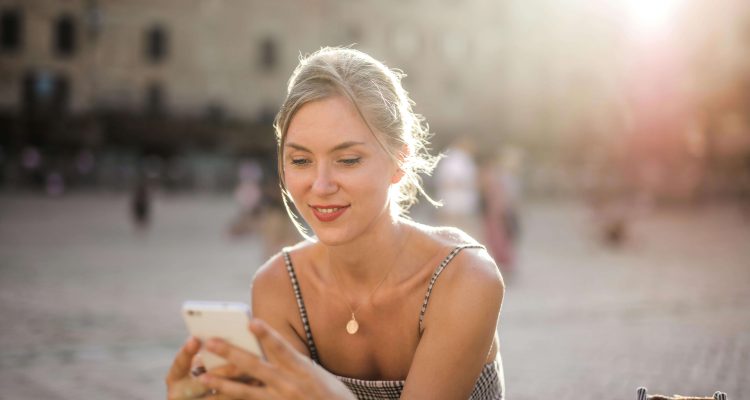 Modern Sugar Baby smiling while texting on her phone, representing digital communication and verified Sugar dating in 2025.