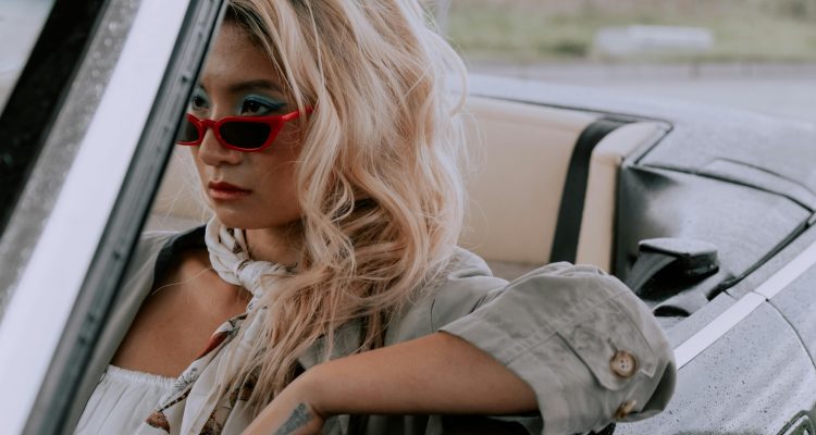 Confident woman wearing red sunglasses sitting in a car, symbolizing emotional independence and self-worth in modern Sugar dating.