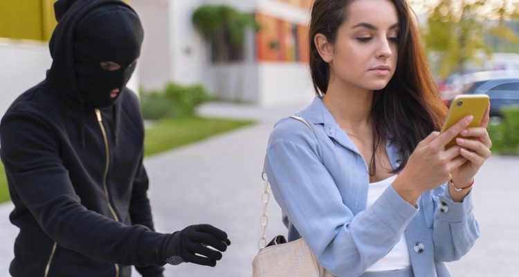 女子專注看手機時遭蒙面歹徒接近，象徵台灣包養交友詐騙與安全防範的重要性。