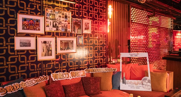 taiwan private party 2026-7 › Sugarbook | The #1 Sugar Daddy & Sugar Baby Dating website to meet Sugar Daddies & Sugar Babies. Build relationships, discuss allowances and get paid instantly. Cozy red sofa lounge with framed photos on a patterned wall and a cluster chandelier overhead, bottles on a table in a dim neon-lit bar setting.